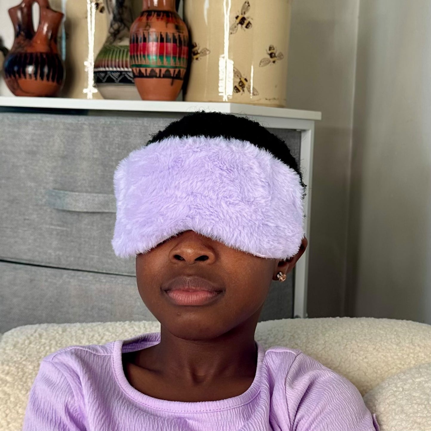 A child wearing the JB Travel World purple fluffy sleep mask.