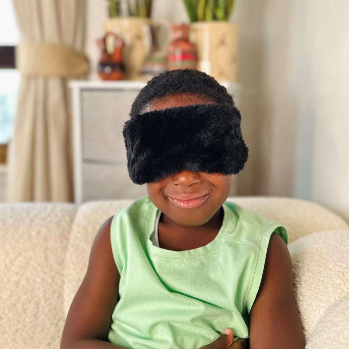 A child wearing the JB Travel World black fluffy sleep mask.