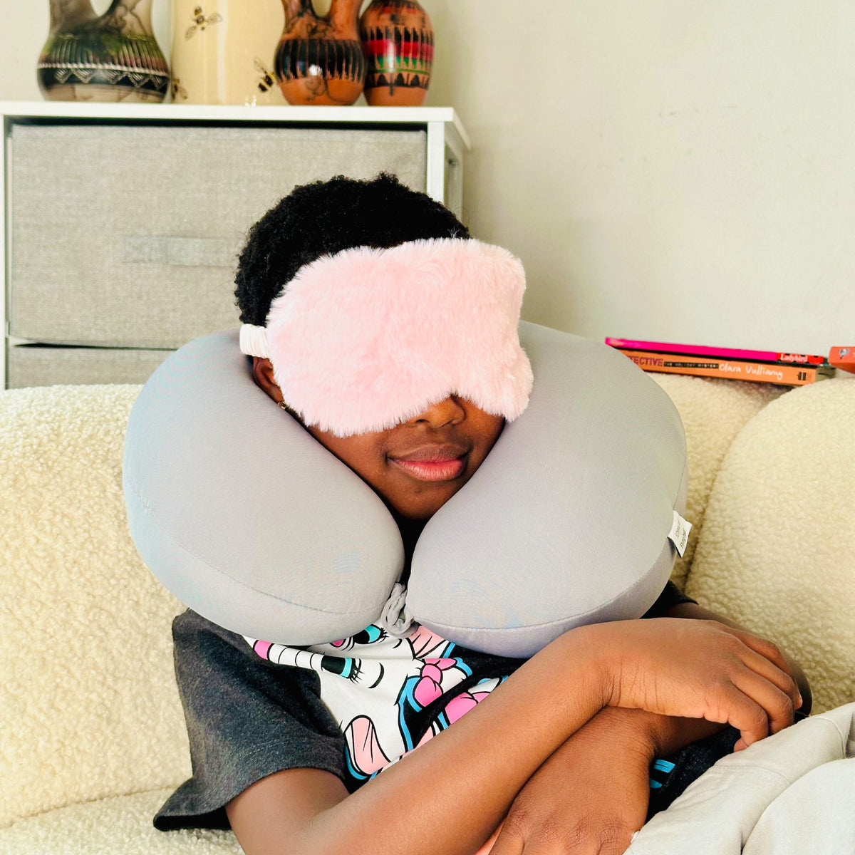 Child resting with JB Travel World Penguin Travel Pillow and pink fluffy sleep mask