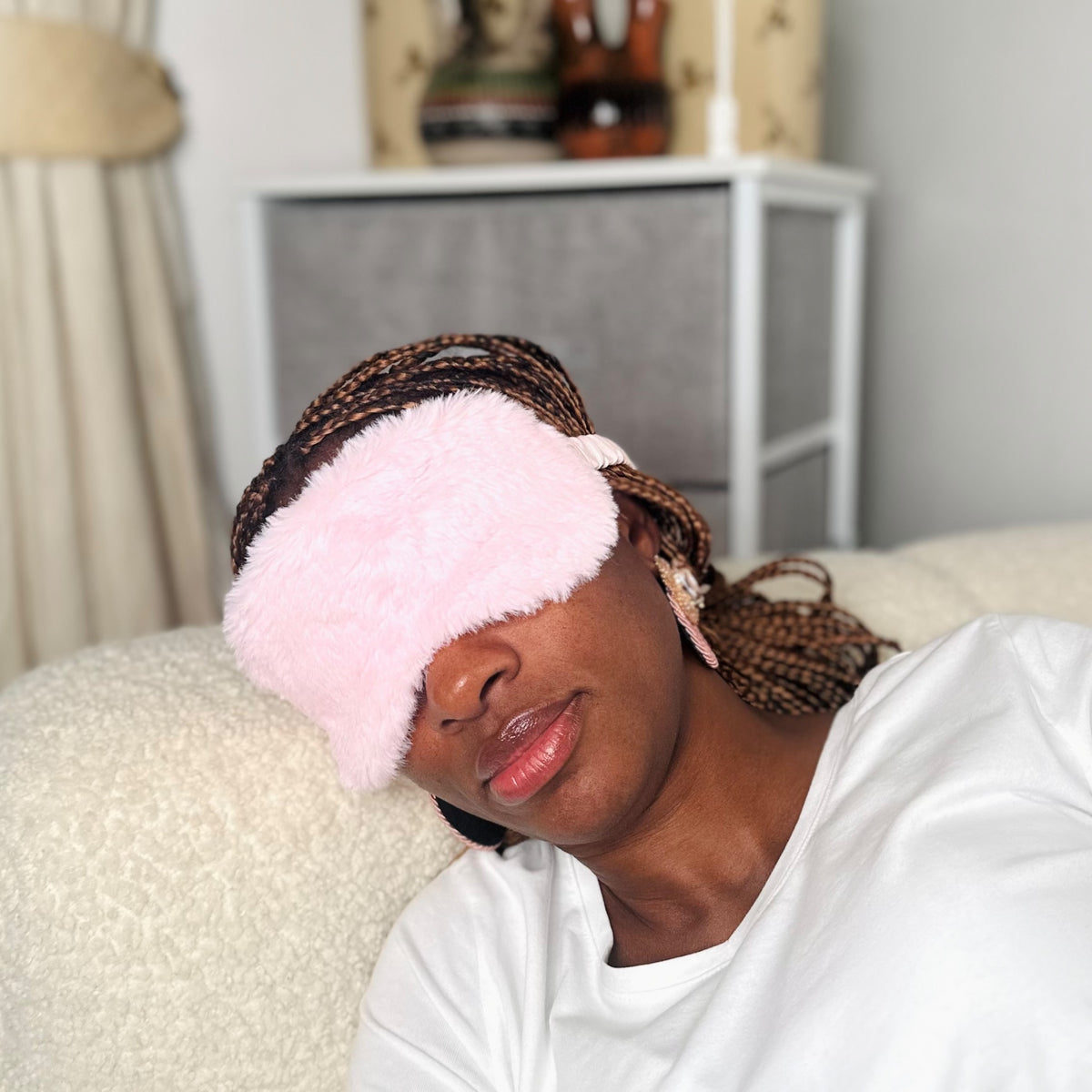 An adult wearing the JB Travel World pink fluffy sleep mask.