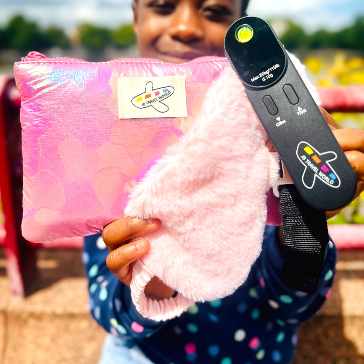 Person holding pink shimmer makeup bag, fluffy eye mask, and digital luggage scale – JB Travel World Travel Essentials Bundle